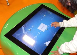 Enfant fait des calculs sur la table multimédia interactive